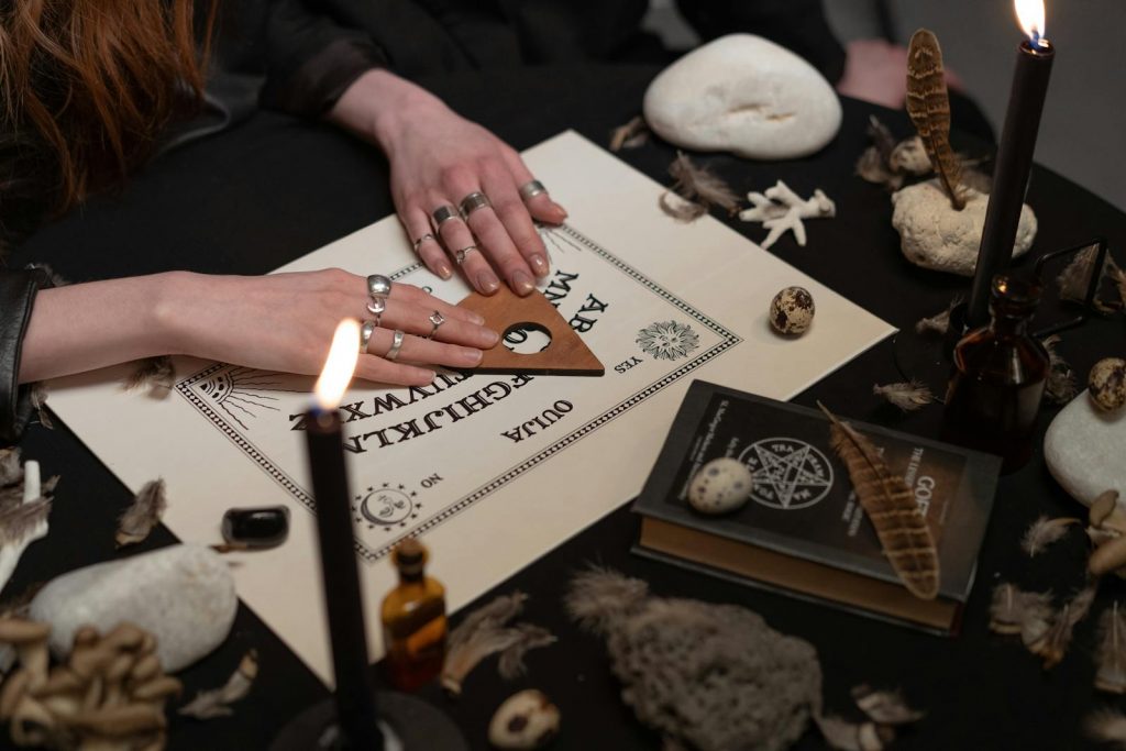 Hands of Women on a Ouija Board Near Burning Candles, Ouija Board Anxiety